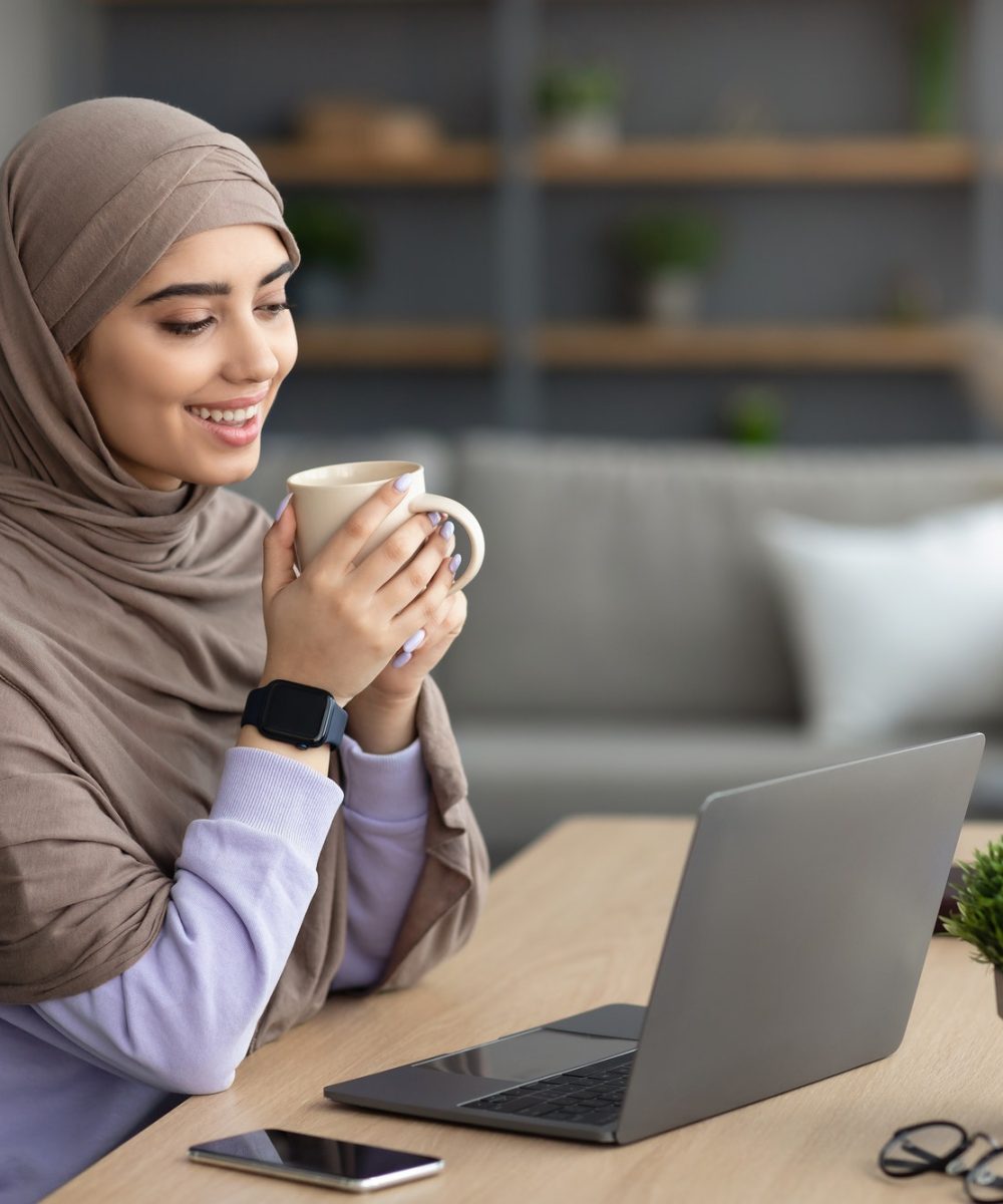 muslim-woman-watching-video-on-computer-drinking-hot-coffee.jpg